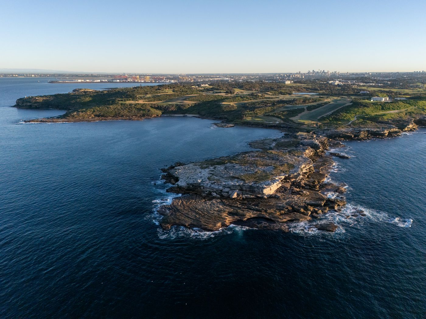 Drone view of the rocky headland with the Sydney skyline beyond